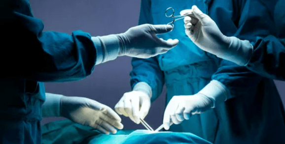 Surgeon in scrubs preparing laparoscopic instruments before an operation